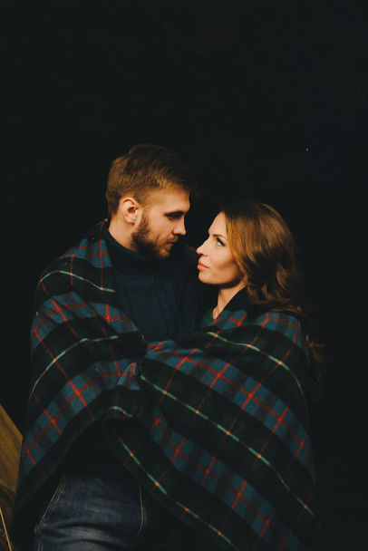 Молодая пара влюбленных туристов, сидящих у костра против палатки в лесу с ретро гирляндой, фото с большим количеством шума, избирательный фокус
 - Фото, изображение