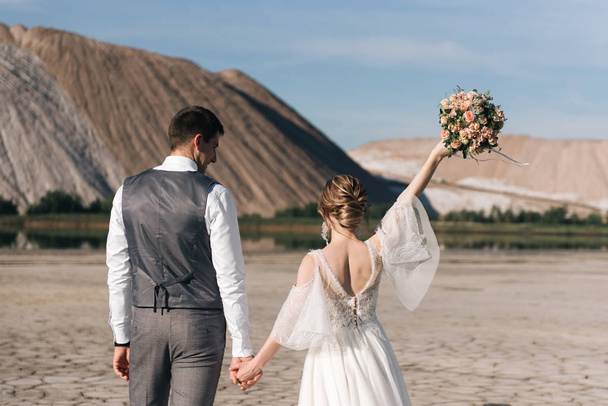 Beautiful elegant couple of newlyweds in love on a beautiful natural background of salt mountains and quarries - Фото, изображение