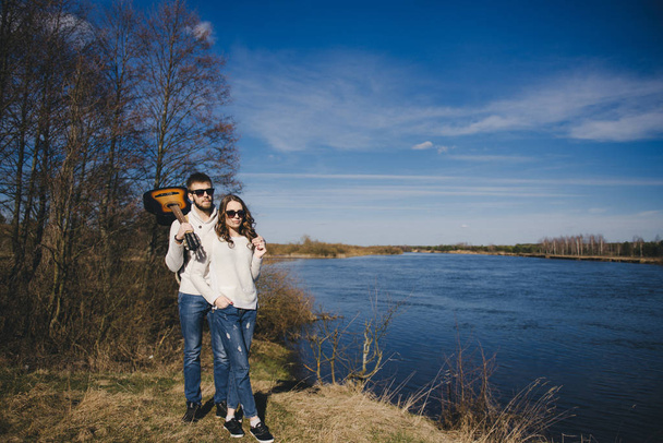 Happy girl and guy with guitar on the river, travel love story concept - Photo, Image