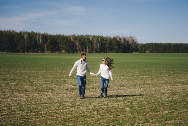 Happy girl and guy running and hugging on the field, love story travel concept, selective focus - Foto, immagini
