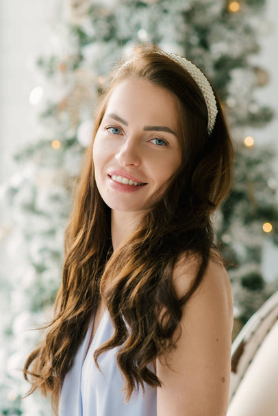 Portrait of an attractive young girl on the background of a Christmas tree - Foto, imagen