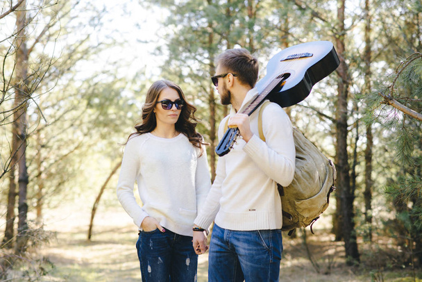 Happy girl and guy with tourist backpack and guitar walking in nature, travel love story concept, selective focus - Zdjęcie, obraz