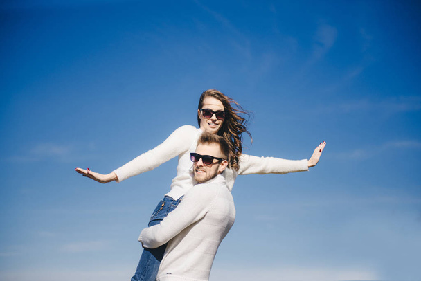 Happy girl and guy running and hugging in flight against the sky, travel love story concept, selective focus - Φωτογραφία, εικόνα