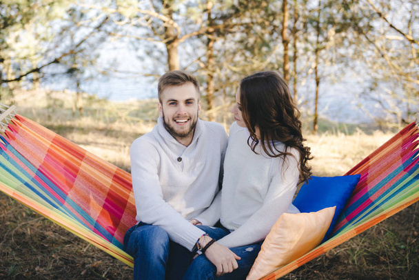 Couple in love, girl and guy in hammock enjoys in the woods, travel love story concept - 写真・画像