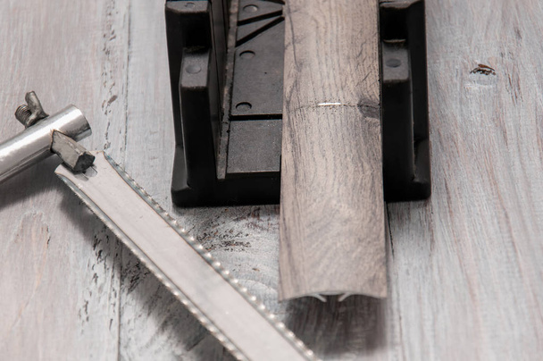Tools on a gray wooden table. Hacksaw for metal, miter box, screwdriver, screws, dowels, sills for interior doors. - Zdjęcie, obraz