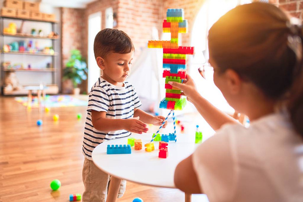 Belo professor e menino brincando com blocos de construção torre de bulding no jardim de infância
 - Foto, Imagem