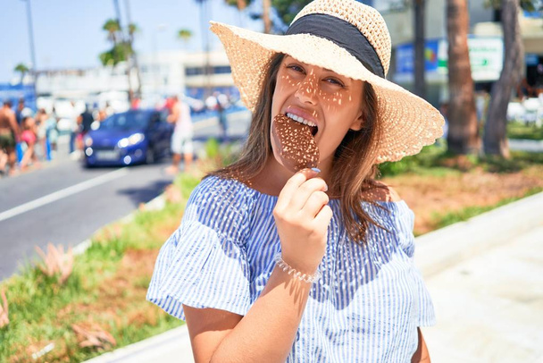 Young beautiful woman eating ice cream cone walking down the street of Tenerife on a sunny day of summer on holidays - Photo, Image