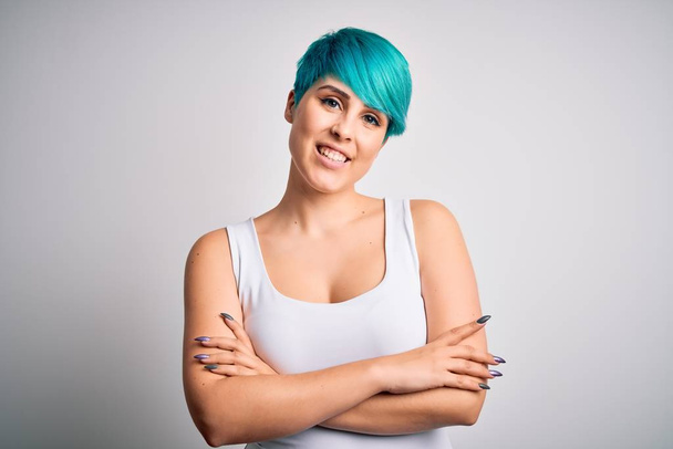 Young beautiful woman with blue fashion hair wearing casual t-shirt over white background happy face smiling with crossed arms looking at the camera. Positive person. - Photo, Image
