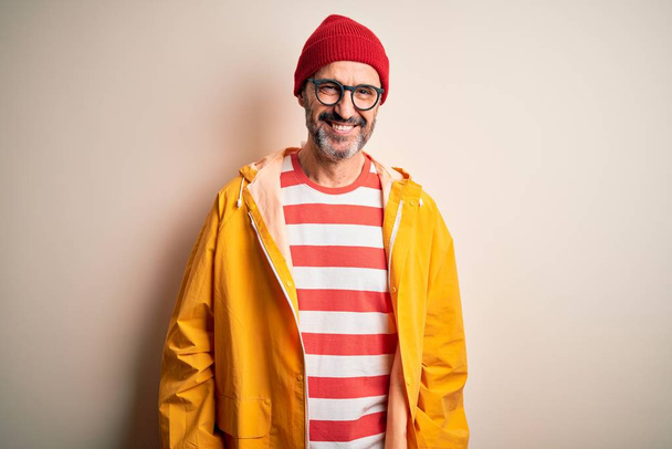 Middle age hoary man wearing glasses and rain coat standing over isolated white background with a happy and cool smile on face. Lucky person. - Photo, Image