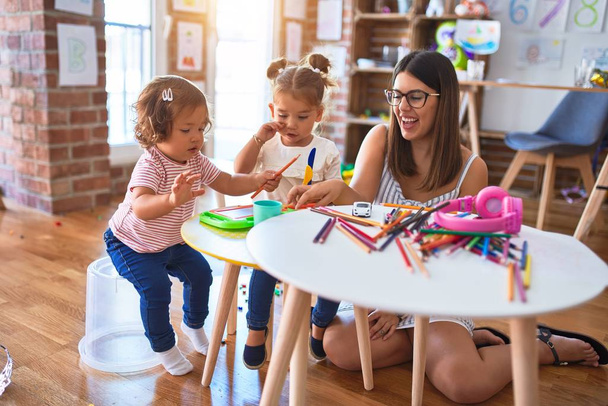 Молодий красивий вчитель і малюки грають в їжу з використанням пластикової їжі та столових іграшок в дитячому саду
 - Фото, зображення