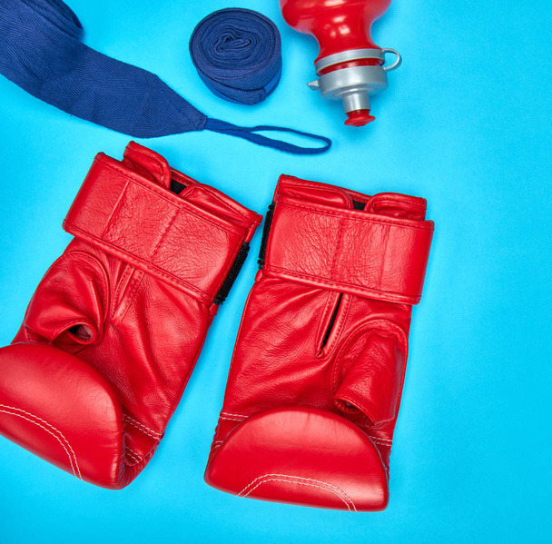 pair of red leather boxing gloves and a textile bandage on a blue background - Photo, image