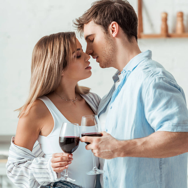 side view of handsome man and attractive woman holding wine glasses  - Foto, afbeelding