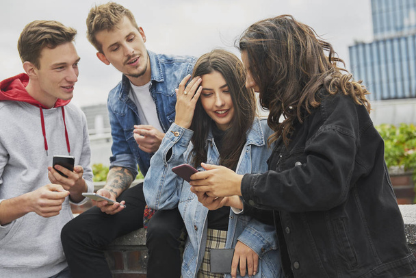 Grupa przyjaciół korzystających z telefonu komórkowego w mieście  - Zdjęcie, obraz