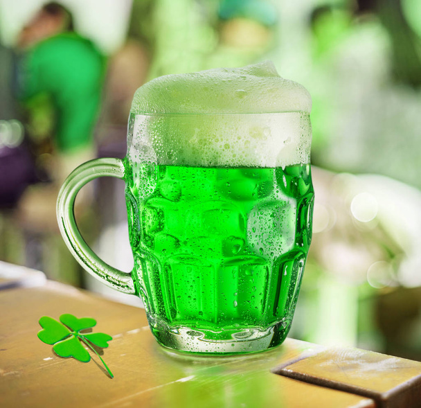 Glass of green beer stands on a table in a pub during the celebr - Fotografie, Obrázek