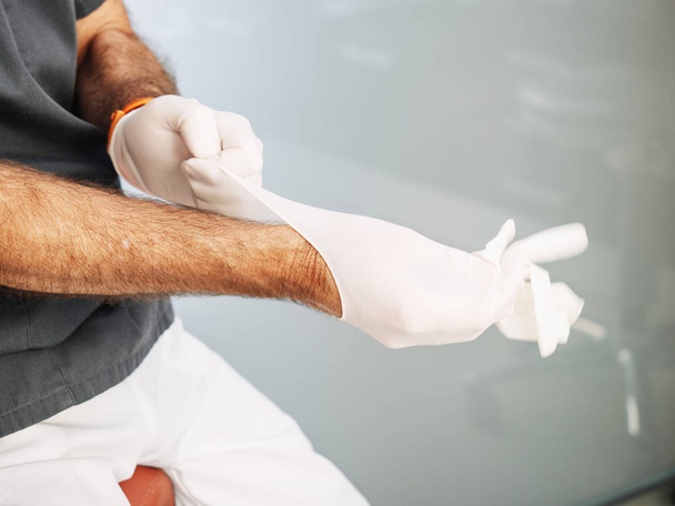 Arzt zieht Latex-Handschuhe an, bevor er seine Arbeit verrichtet - Foto, Bild