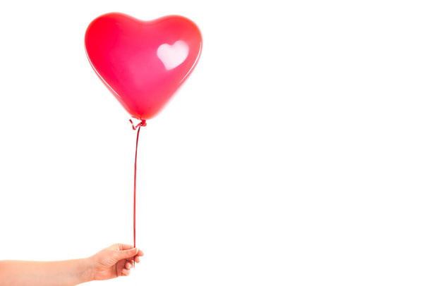 Female hand holds red rubber inflatable heart shape balloon. Love, relationship, valentines day and birthday celebration concept. Studio shot on an abstract blurred background with blank copy space - Foto, Imagem