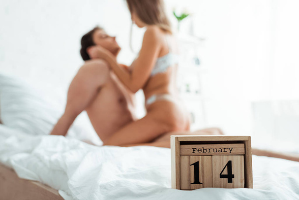 selective focus of wooden cubes with 14 february near sexy couple  - Foto, Imagen