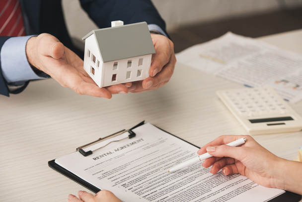 cropped view of agent holding house model near woman with pen in hand  - Photo, Image