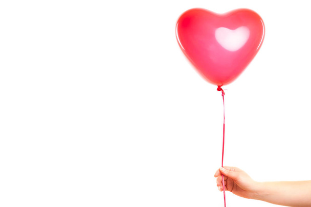 Female hand holds red rubber inflatable heart shape balloon. Love, relationship, valentines day and birthday celebration concept. Studio shot on an abstract blurred background with blank copy space - Foto, Imagem