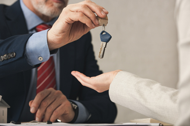 cropped view of realtor giving key to woman in office  - Photo, Image