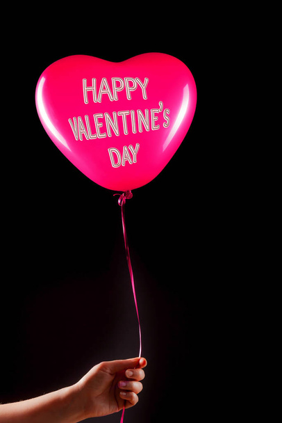 Female hand holds red rubber inflatable heart shape balloon. Love, relationship, valentines day and birthday celebration concept. Studio shot on an abstract blurred background with blank copy space - Foto, afbeelding