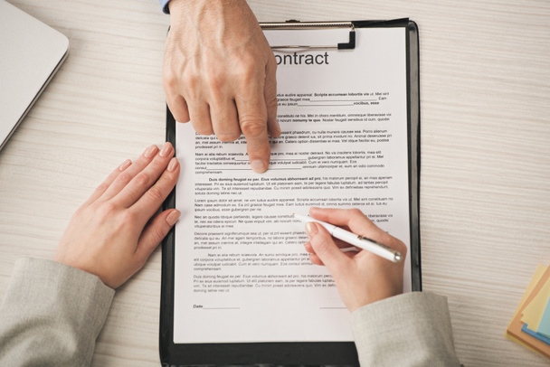 cropped view of agent pointing with finger at clipboard with contract lettering near woman  - Photo, Image