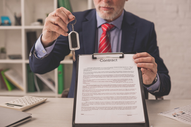 cropped view of bearded agent holding clipboard with contract lettering and car key  - Photo, Image