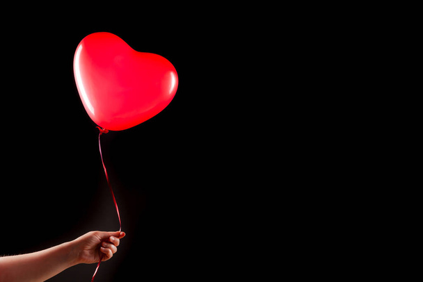 Female hand holds red rubber inflatable heart shape balloon. Love, relationship, valentines day and birthday celebration concept. Studio shot on an abstract blurred background with blank copy space - Fotografie, Obrázek