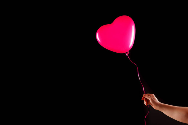 Female hand holds red rubber inflatable heart shape balloon. Love, relationship, valentines day and birthday celebration concept. Studio shot on an abstract blurred background with blank copy space - Photo, image