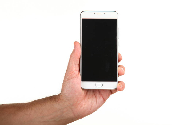 Ihmisen kädessä on moderni älypuhelin, jossa on tyhjä kromaattinen näyttö kämmenessä. Teknologian ja mainonnan käsite. Yksityiskohtainen lähikuva studio ampui eristetty abstrakti hämärtynyt valkoinen tausta
 - Valokuva, kuva