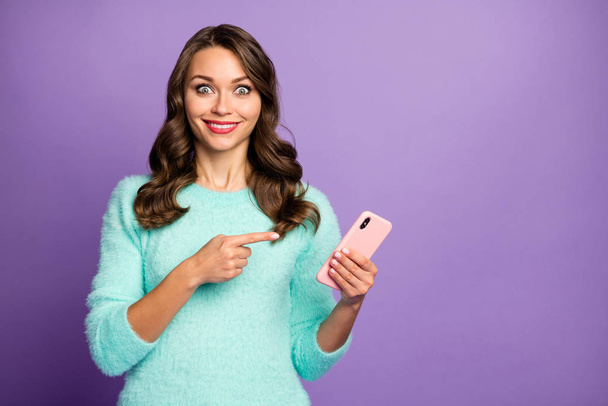 Photo of funny pretty lady hold telephone hands indicating finger on device screen advising cool smart phone sale wear casual pastel fluffy fuzzy sweater isolated purple color background - Photo, Image