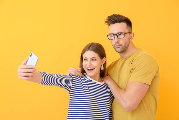 Young couple taking selfie on color background - Foto, Imagen