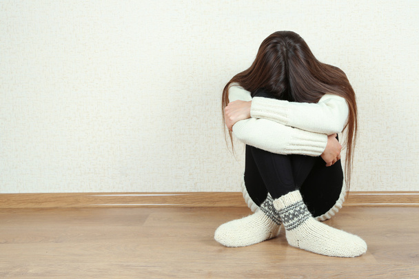 Sad woman sitting on floor near wall - Фото, зображення