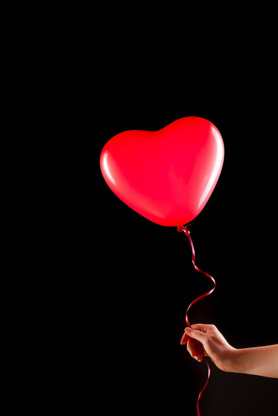 Female hand holds red rubber inflatable heart shape balloon. Love, relationship, valentines day and birthday celebration concept. Studio shot on an abstract blurred background with blank copy space - Valokuva, kuva
