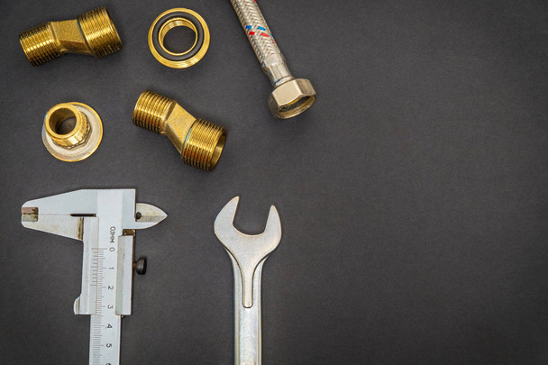 Set of tools and spare parts for plumbing on black background with space for advertising - Photo, Image