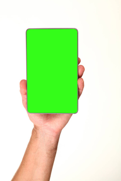 Human hand holds a modern smartphone with a blank chromakey screen in a palm. Technology and advertising concept. Detailed closeup studio shot isolated on abstract blurred white background - Fotografie, Obrázek
