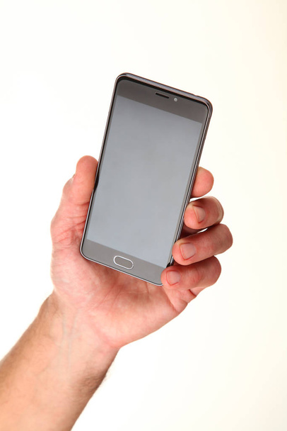 Human hand holds a modern smartphone with a blank chromakey screen in a palm. Technology and advertising concept. Detailed closeup studio shot isolated on abstract blurred white background - Fotó, kép