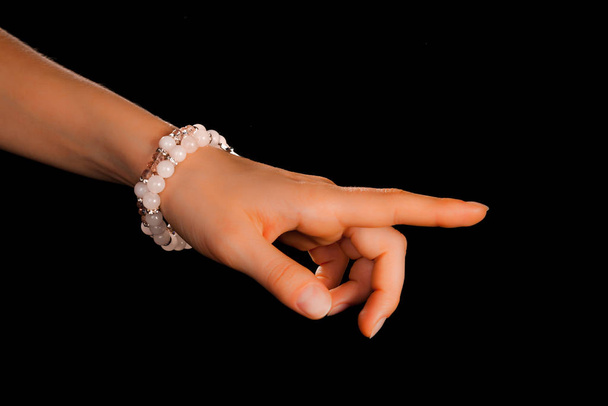 Mooie elegante handgemaakte sieraden edelsteen armband met kleurrijke glanzende kralen op een ontspannen vrouwelijke pols met neutrale manicure. Mode en handwerk accessoire concept. Close-up met zachte selectieve focus - Foto, afbeelding