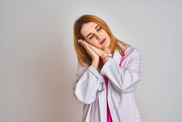 Zrzavý kavkazský lékař žena na sobě růžový stetoskop přes izolované pozadí spaní unavený snění a pózování s rukama dohromady a zároveň se usmívá se zavřenýma očima. - Fotografie, Obrázek