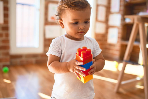 Imádnivaló kisbaba játszik építőkockák körül sok játék óvodában - Fotó, kép
