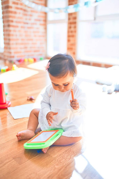 Mooi kind blij op de kleuterschool rond kleurrijke speelgoed tekening op magnetisch schoolbord - Foto, afbeelding