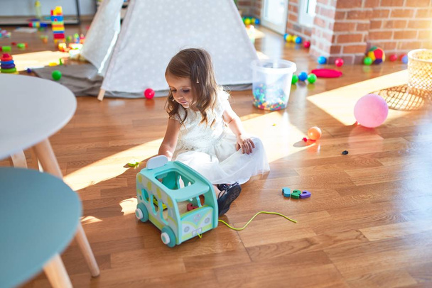 entzückendes blondes Kleinkind spielt im Kindergarten mit Auto-Spielzeug um jede Menge Spielzeug - Foto, Bild