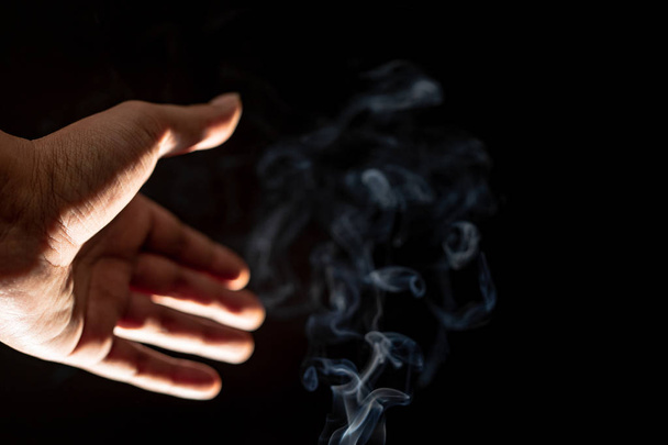 A close up of hand showing and smoky black background - Фото, изображение