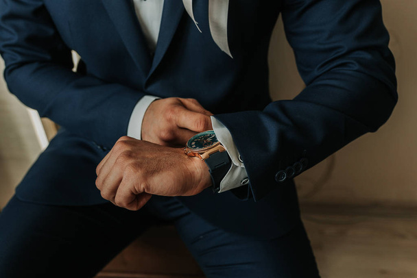 podnikatel v černém kostýmu větru hodiny (náramkové hodinky) na ruce - Fotografie, Obrázek