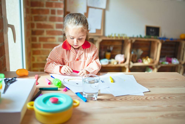 Beautiful blond toddler girl wearing school uniform drawing with colored pens at kindergarten - Фото, зображення