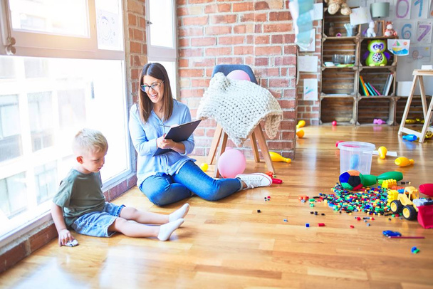 Mujer terapeuta joven que habla con el niño, consejero y corrección de comportamiento en la oficina alrededor de los juguetes
 - Foto, imagen