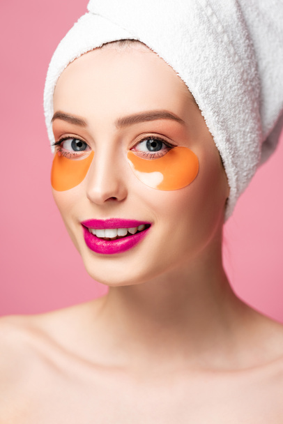 smiling naked girl with eye patches on face looking at camera isolated on pink  - Foto, Bild