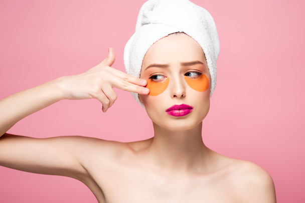 nackte Mädchen berühren Gesicht mit Augenklappen isoliert auf rosa  - Foto, Bild