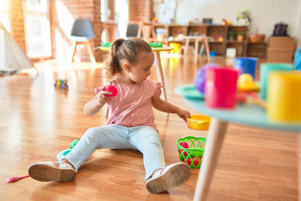 Hermosa niña rubia jugando comidas usando comida plástica en el jardín de infantes
 - Foto, Imagen