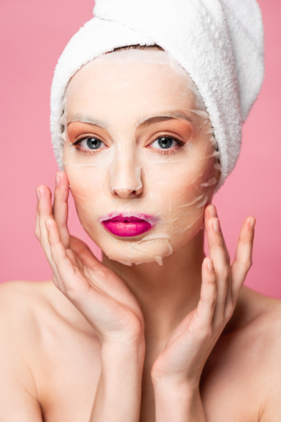young naked woman in moisturizing face mask touching face isolated on pink  - Foto, Bild
